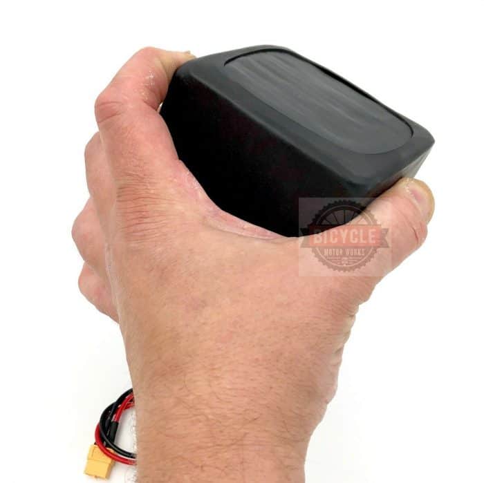 A hand holding a remote control in one hand.