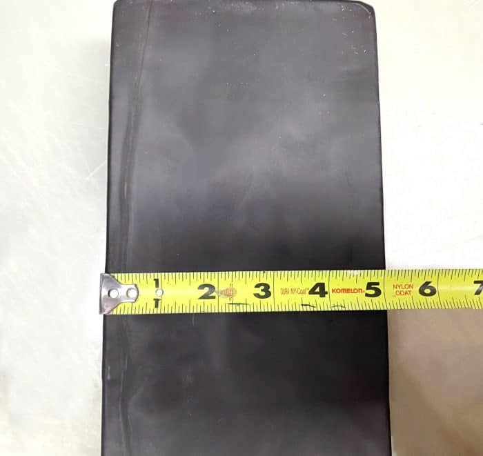 A black book with a yellow measuring tape on top of it.