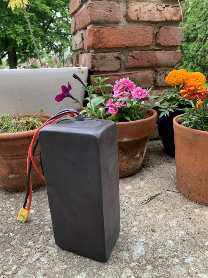 A black box sitting on the ground next to some flowers.