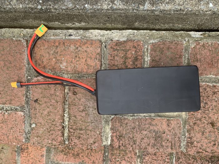 A black box sitting on the ground with wires attached to it.