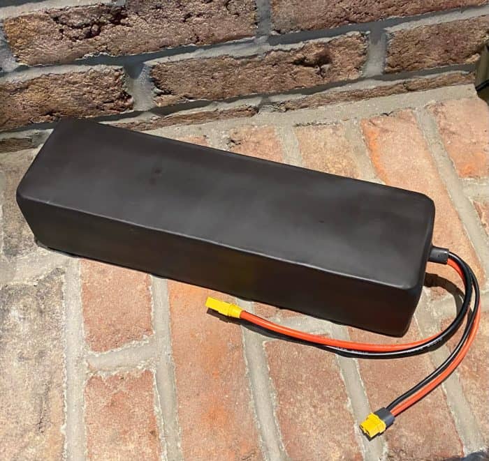 A black battery sitting on top of the brick floor.