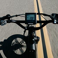 A view of the handlebar and speedometer on a bicycle.