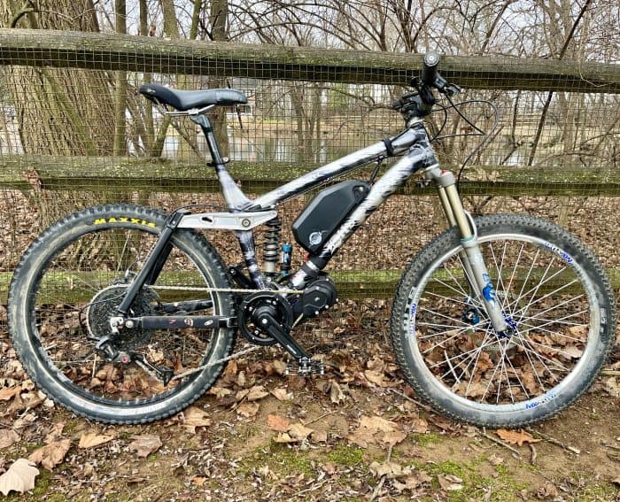 A bicycle parked in the grass near a fence.